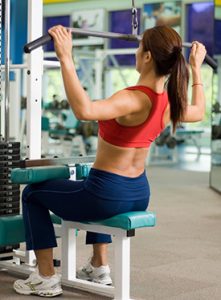 Woman in the gym pulling down weights | Mitchell Medical