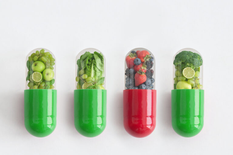 Red vitamin capsule containing antioxidant berries standing out amongst green pills